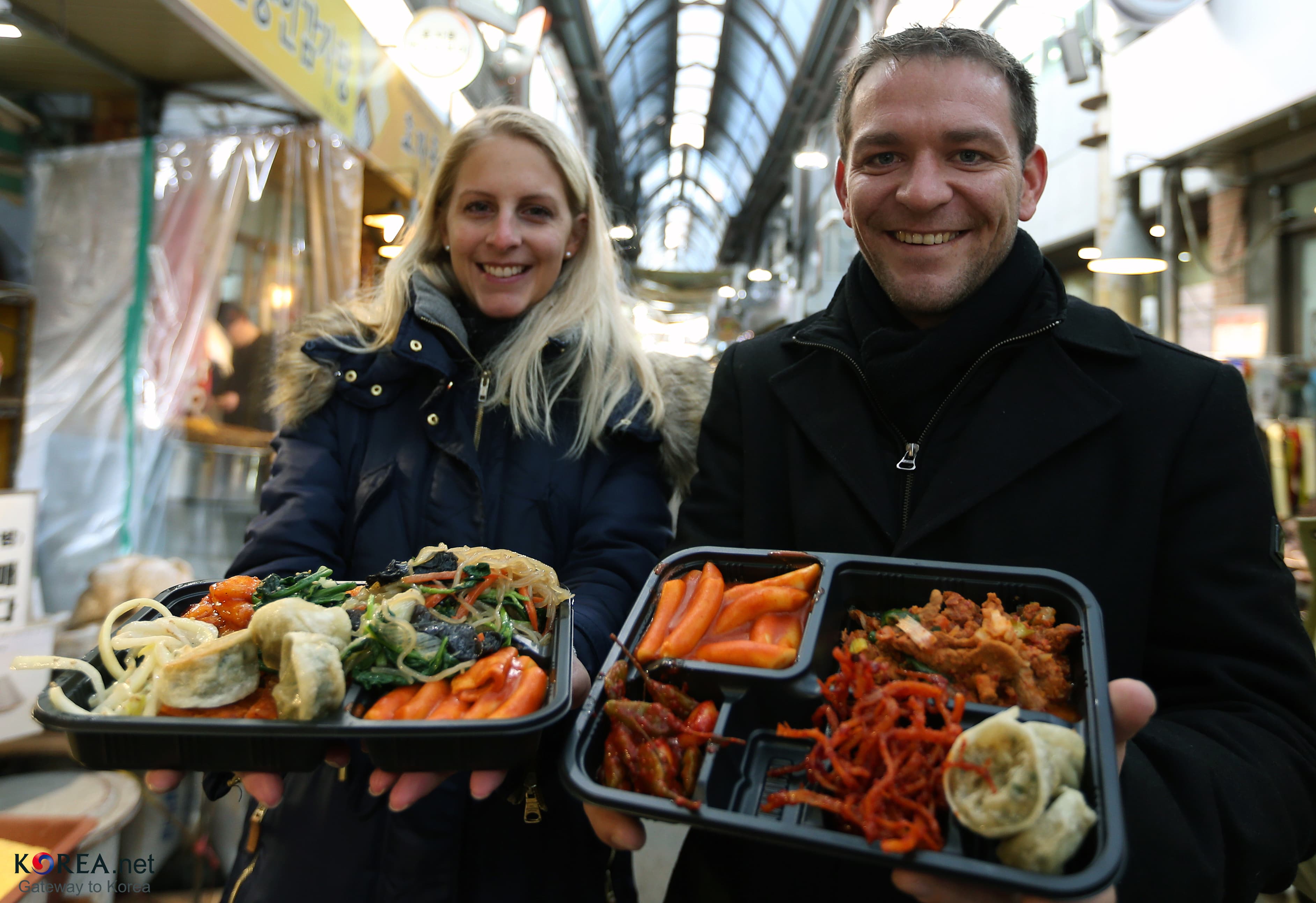 Visitors holding coin-lunch trays from Tongin Market's dosirak cafe