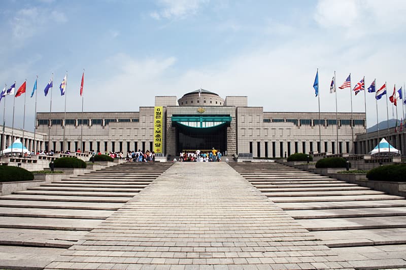 The War Memorial of Korea's main facade, flanked by national flags along the entrance walkway