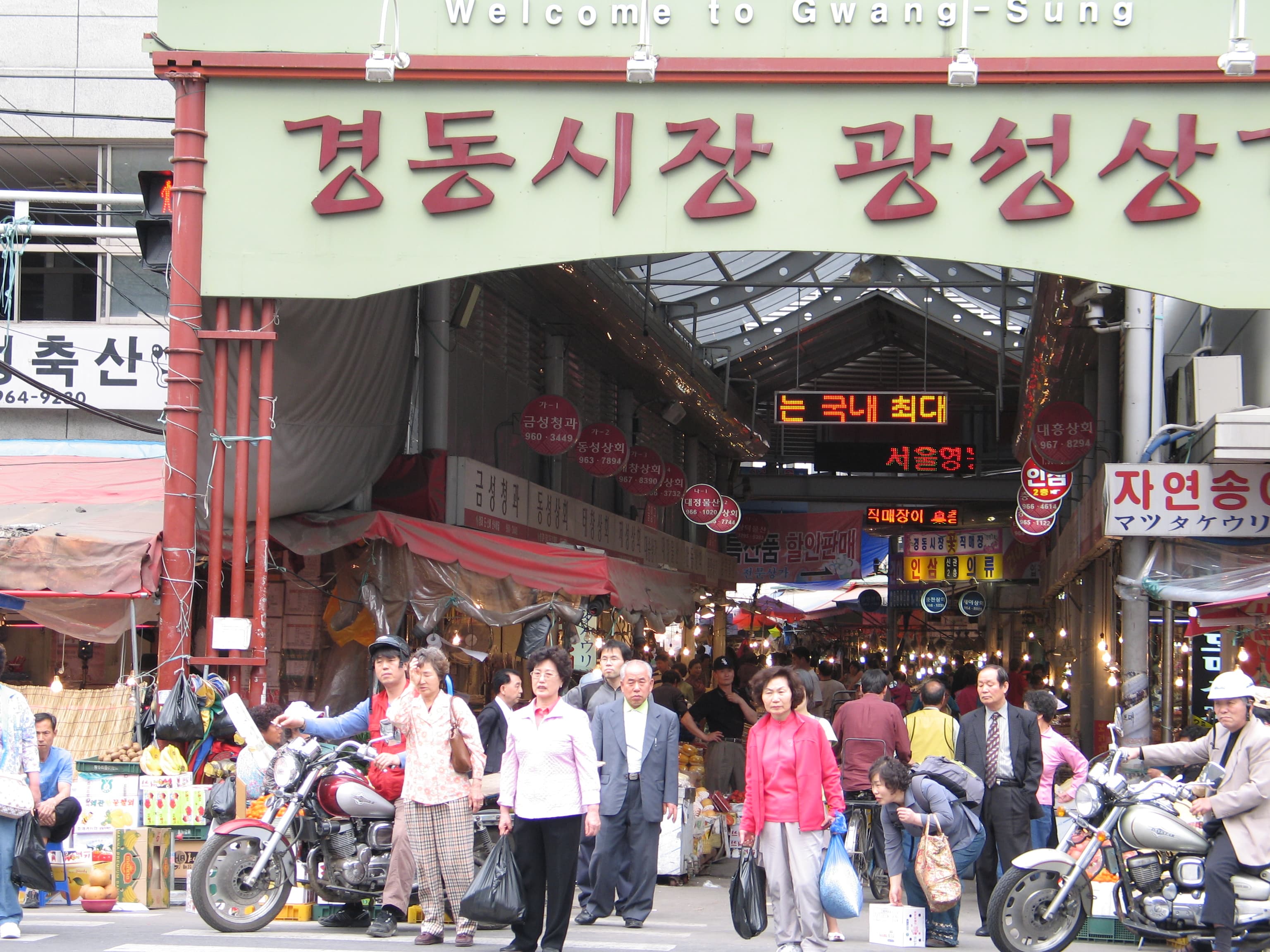 The signed entrance archway to Gyeongdong Market, with its busy alley beyond