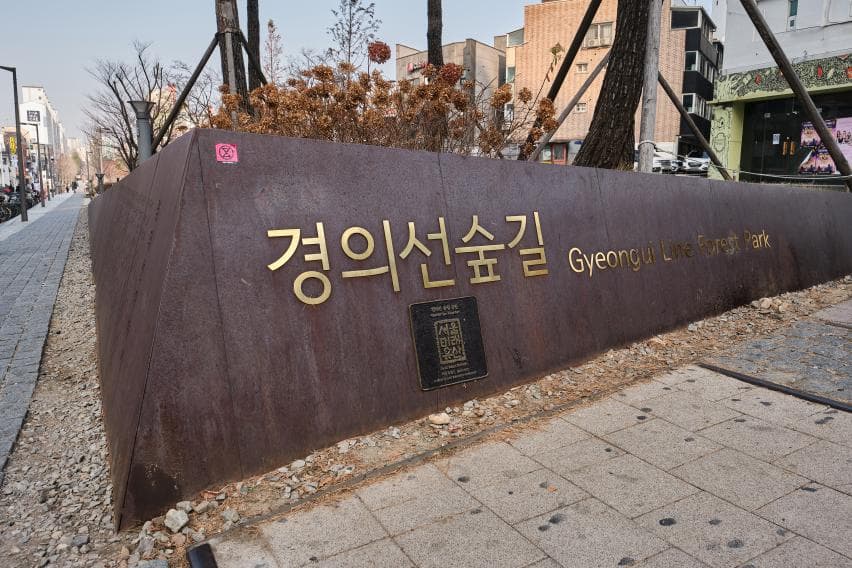The weathered-steel entrance marker reading Gyeongui Line Forest Park beside the Yeonnam-dong path