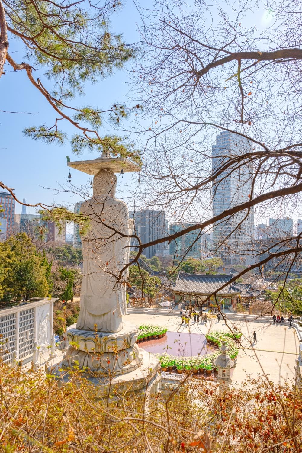 The standing Maitreya at Bongeunsa with the Gangnam high-rises and the temple's tiled roofs behind it