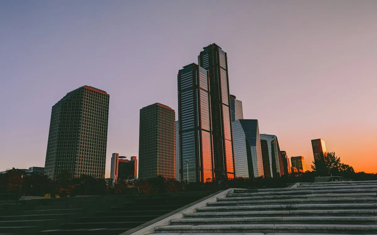 A high-rise business-district skyline above stone steps at sunset