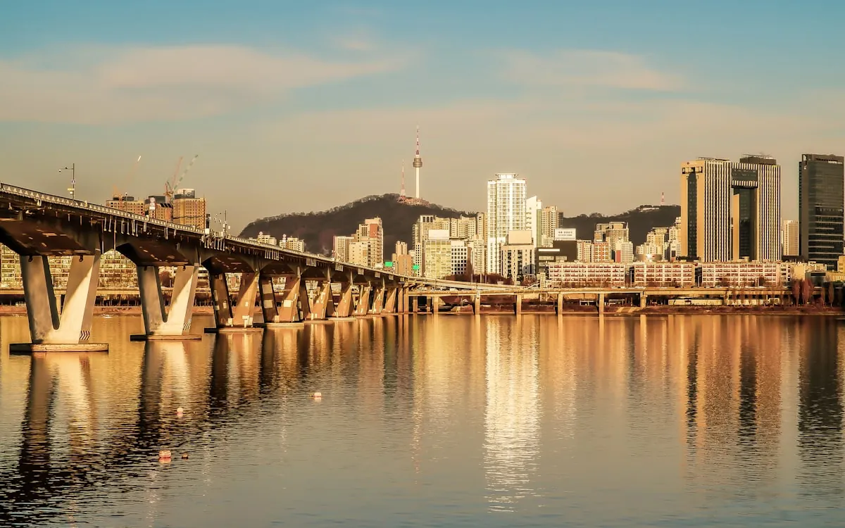 A city skyline and a river bridge at sunset