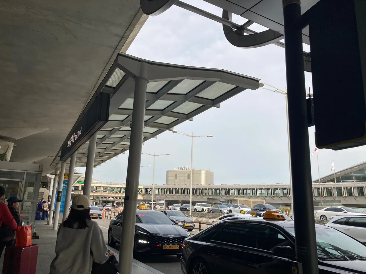The designated taxi stand at Incheon Airport Terminal 1: taxis queueing under a canopy marked Taxi Stand, with passengers waiting beside their luggage