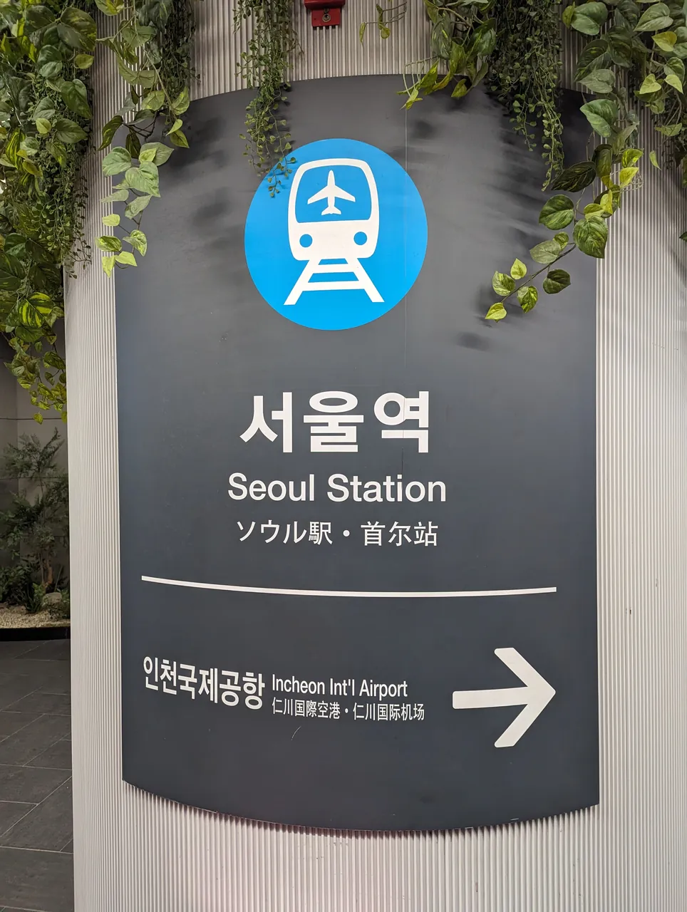 The airport railway station sign at Seoul Station, reading Seoul Station in Korean, English, Japanese and Chinese beneath the AREX train-and-aeroplane symbol