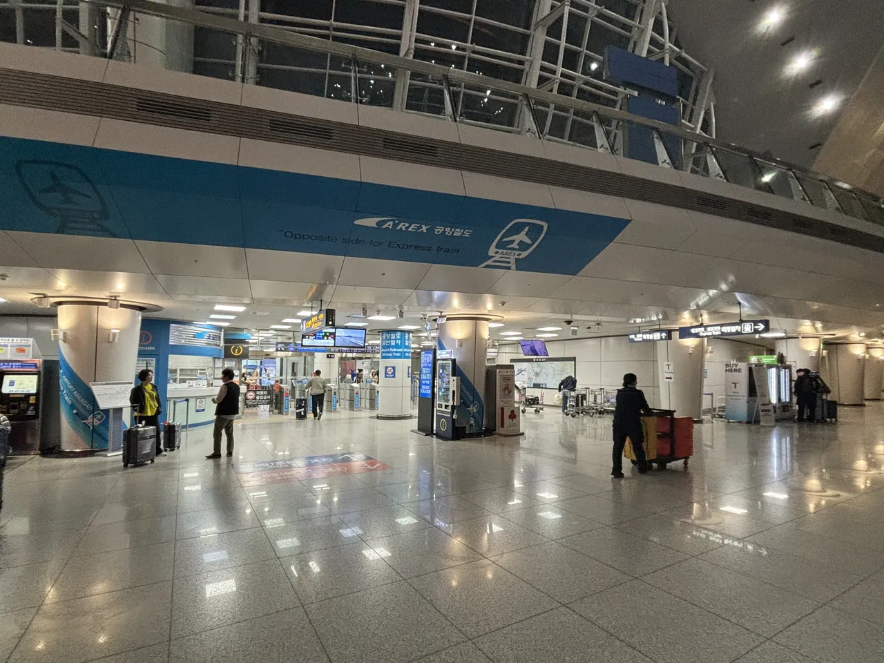 The AREX all-stop train concourse at Incheon Airport Terminal 1, its blue banner reading Opposite side for Express train above a row of ticket gates
