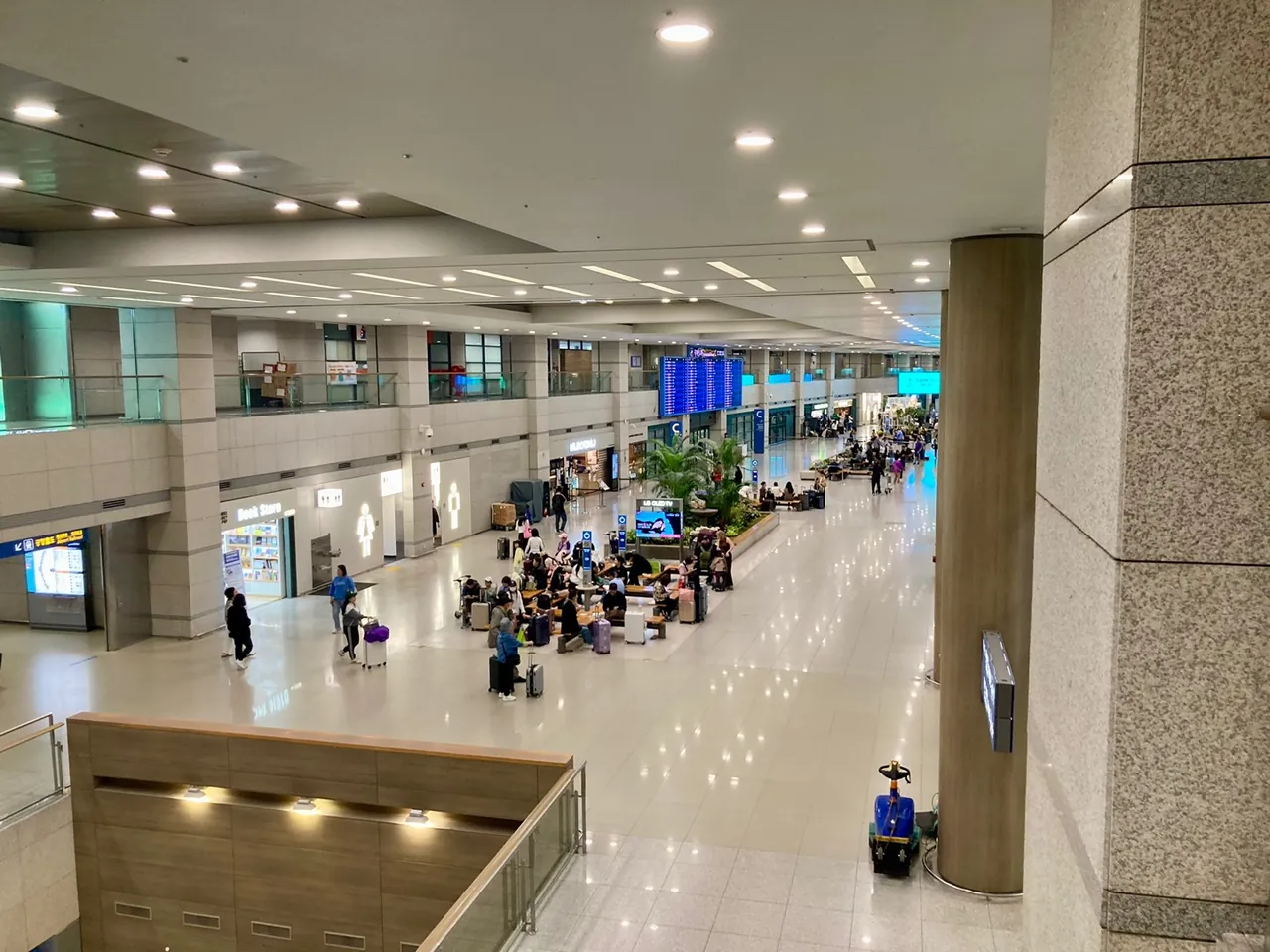 The arrivals hall at Incheon Airport Terminal 1: passengers wheeling luggage out past people waiting, with the arrivals board further in