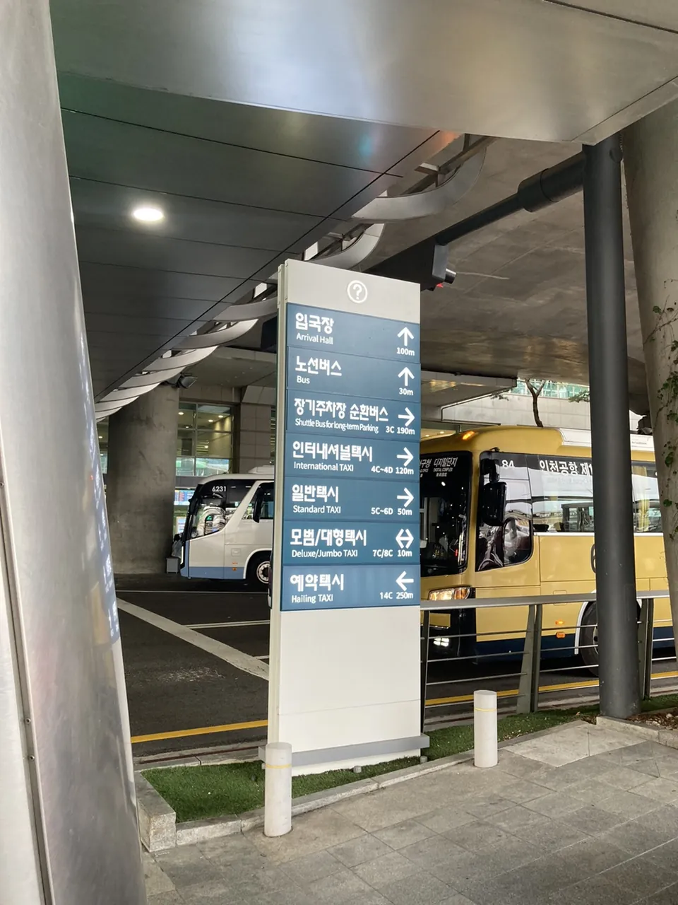 A boarding-point directory outside Terminal 1, listing the arrival hall at 100m, buses at 30m, international taxis at 4C–4D, standard taxis at 5C–6D, deluxe and jumbo taxis at 7C and 8C, and hailing taxis at 14C, each with a direction arrow