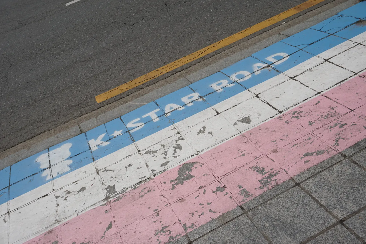"K★STAR ROAD" painted with blue, white and pink stripes along the pavement of K-Star Road in Gangnam